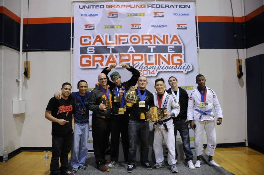 Grappling champions posing with medals and belts