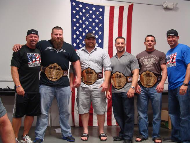 Six men with title belts before U.S. flag