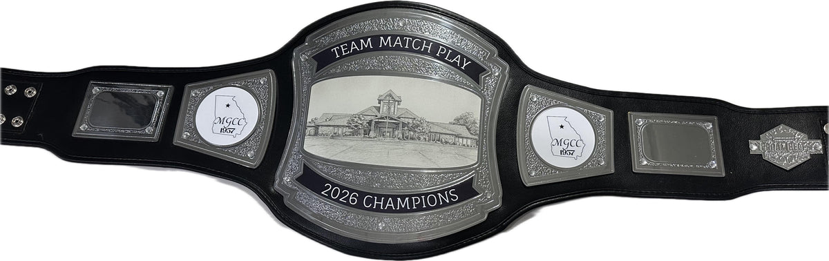 A golf championship belt with a large central silver-toned plate reading 'TEAM MATCH PLAY 2026 CHAMPIONS' and 'MCCY 2026,' flanked by two smaller silver plates and black straps on a white background.