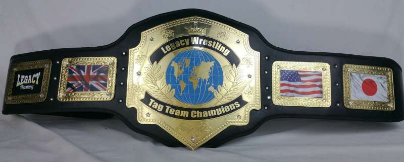 A black and gold Legacy Wrestling Team Champions belt with decorative panels featuring the Union Jack, American flag, and Japanese flag.
